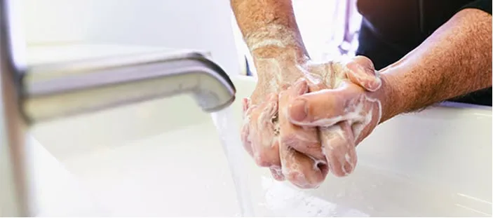 Un lavage des mains au savon sous un robinet.